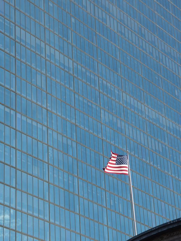 American flag flying on a rooftop before the John Hancock building in Boston MA