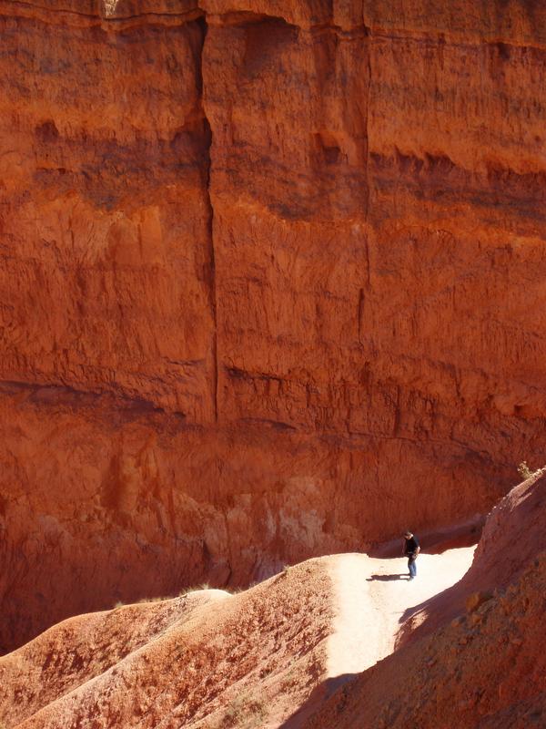 sunlit hiker dwarfed amidst the hoodoos at Bryce Canyon National Park in Utah