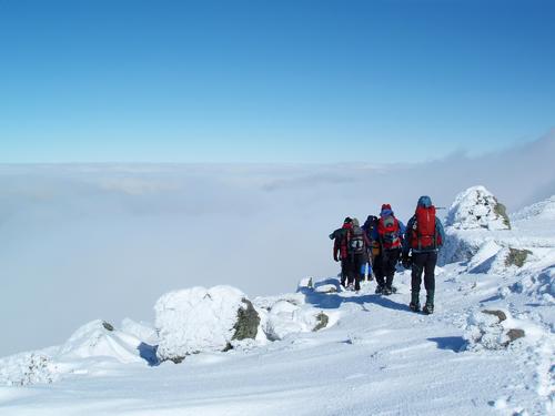 winter hikers descend from Mount Adams in New Hampshire toward an undercast cloud layer