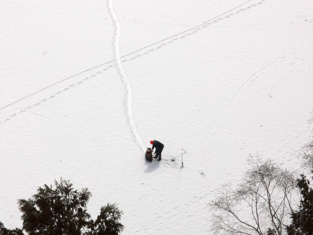 ice fisherman in March as seen from the cliff edge of Allen Hill at Shelburne Bay Park in Vermont