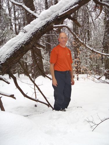 winter hiker on the summit of Bear Hill at Bear Brook State Park in New Hampshire