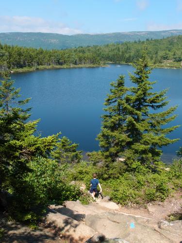 young hiker on the way down toward The Bowl off the backside of The Beehive at Acadia National Park in Maine