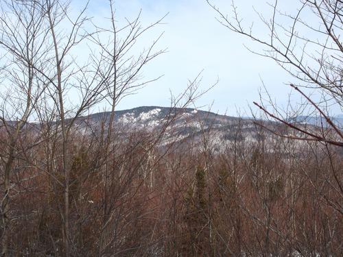 through-the-trees view of Plymouth Mountain from the summit of Bridgewater Mountain in New Hampshire