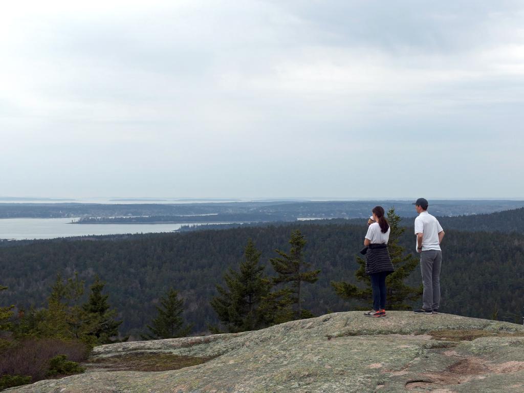 a pair of hikers checks the view near the summit of Day Mountain at Acadia National Park in Maine