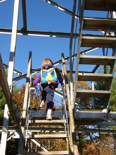 young hiker headed up the fire lookout tower on Federal Hill in New Hampshire