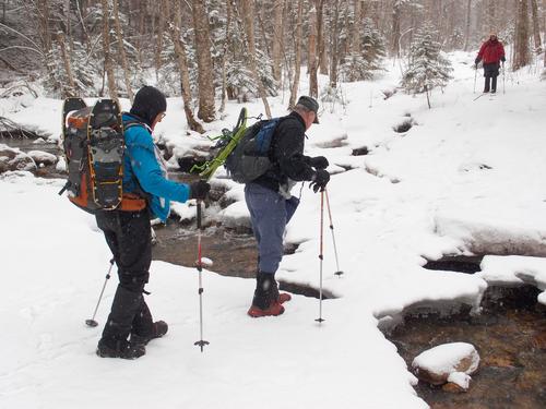 early-spring hikers about to cross an iffy ice bridge on the way to Mount Garfield in New Hampshire