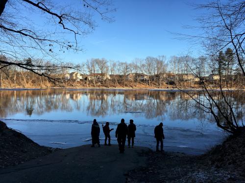 hikers in January on the Merrimack River boat ramp at Greeley Park in New Hampshire