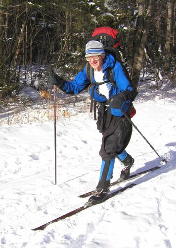 winter hiker skiing the access road to Mount Hale in New Hampshire