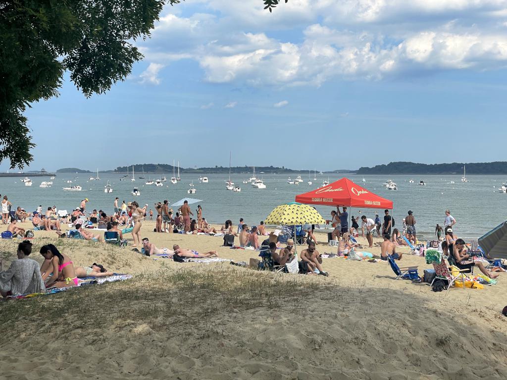 beachgoers in June on a sunny Sunday afternoon beside Boston Harborwalk in Massachusetts