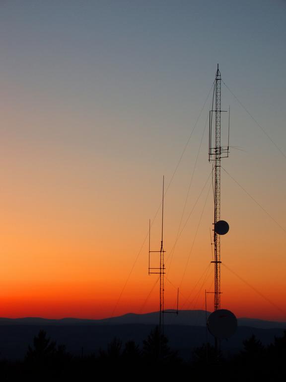 the sun sets behind communication towers as seen from Hyland Hill in western New Hampshire