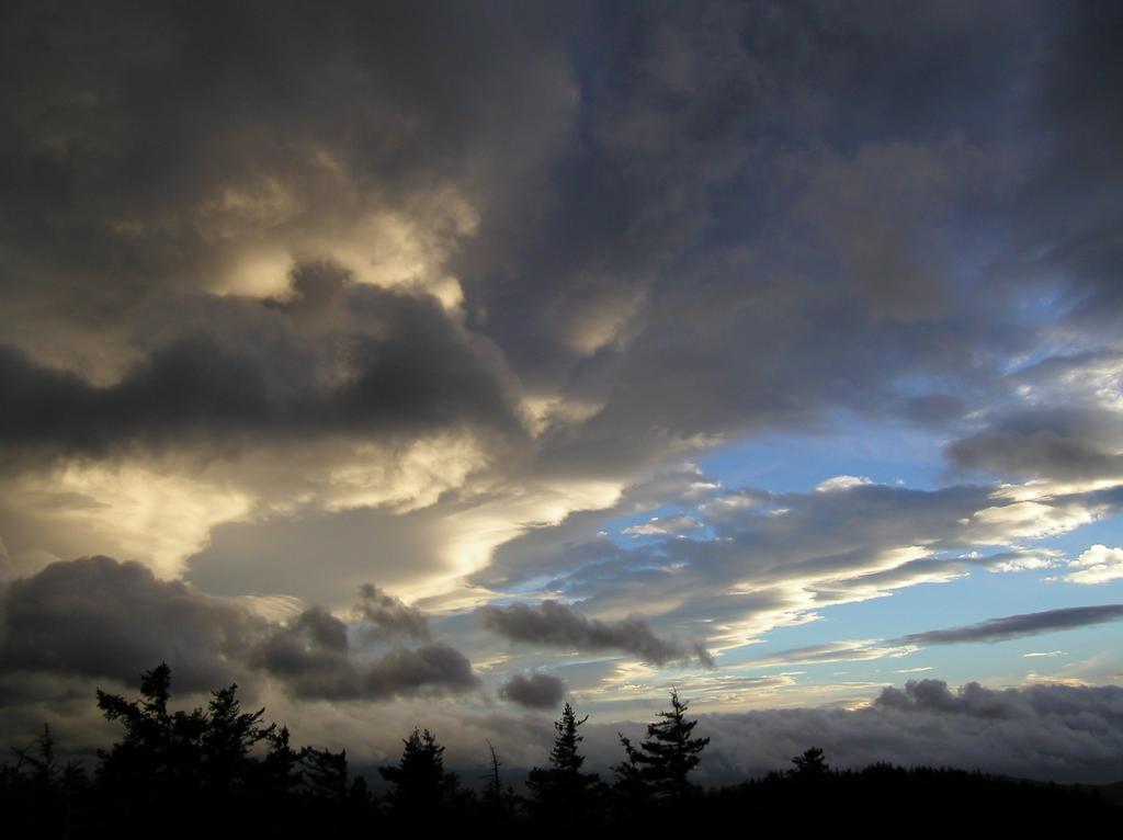 dissipating storm clouds seem to explode overhead as seen near sunset from Mount Israel in the White Mountains of New Hamphsire