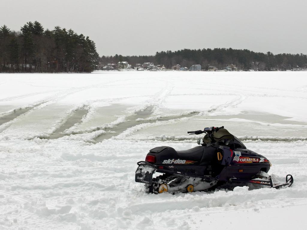 snowmobile and wet pond tracks in February at Kingston State Park in southeast New Hampshire