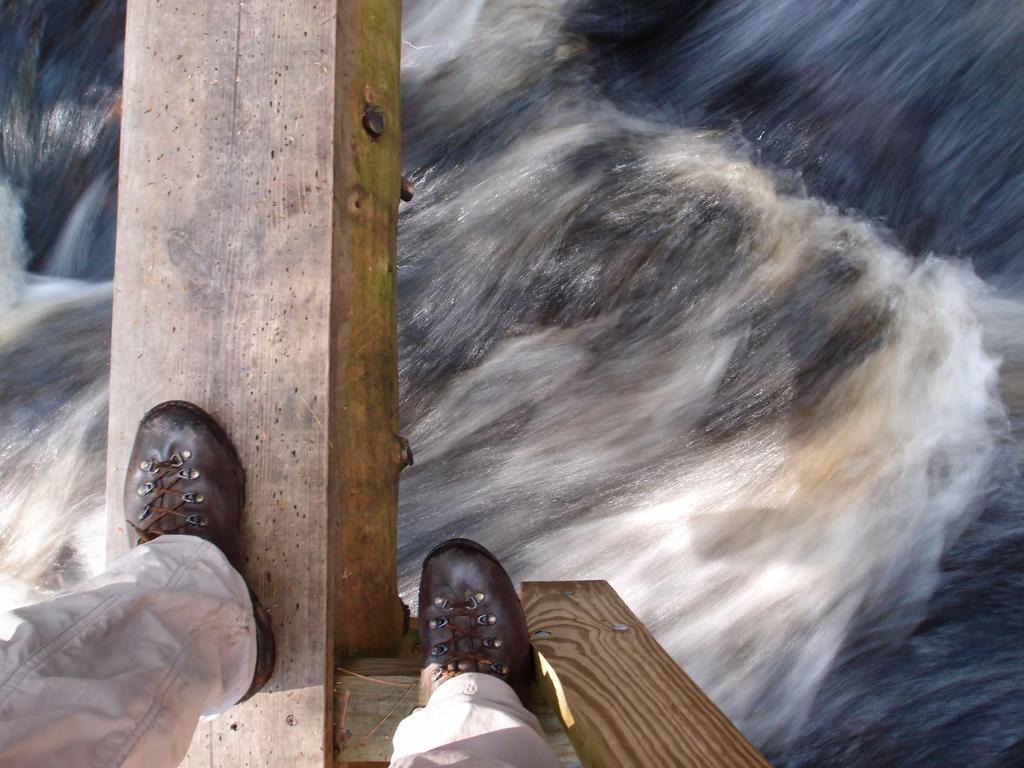 hiker feet on a narrow bridge crossing Purgatory Brook in southern New Hampshire