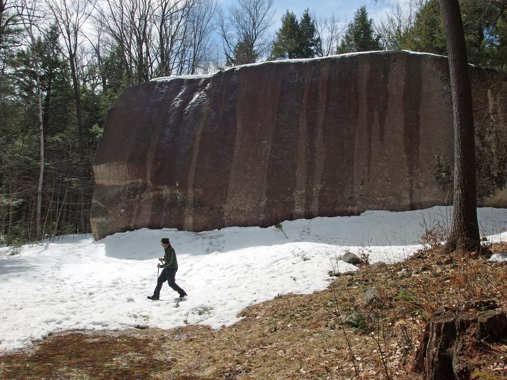 Dick hikes past Madison Boulder at Madison Boulder Natural Area in New Hampshire