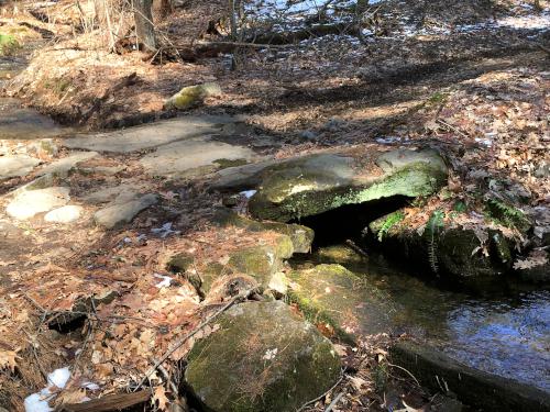 old stone bridge crossing a stream at Musquash Conservation Land at Hudson in southern New Hampshire