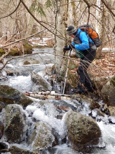 bushwhacker crossing a stream on the way to Osgood Hill in New Hampshire