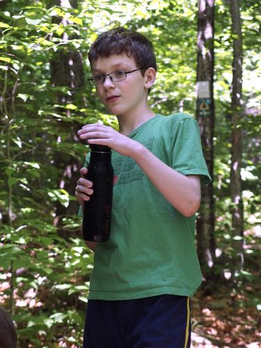 hiker taking a water break on the trail to Piermont Mountain in western New Hampshire