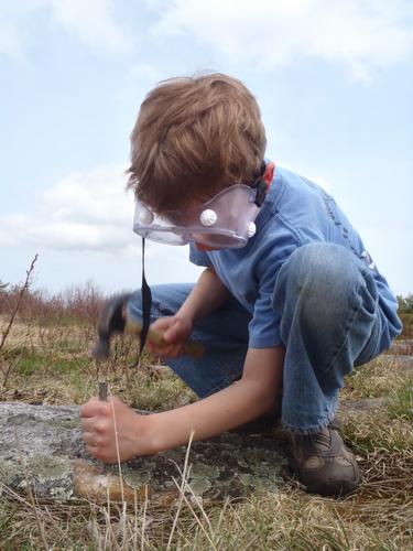 young hiker quarrying rose quartz on Rose Mountain in New Hampshire