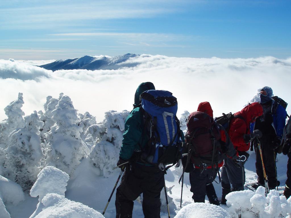 February hikers viewing cloud-enshrouded Franconia Ridge from the summit of North Twin Mountain in New Hampshire