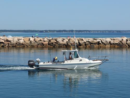 a play boat travels the channel between jettys to go out into the Atlanic Ocean from Wells Harbor in southern Maine