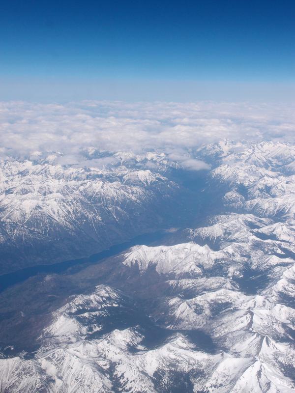 looking-down view of the still-snow-capped mountains of the Continental Divide while flying to Seattle in Washington